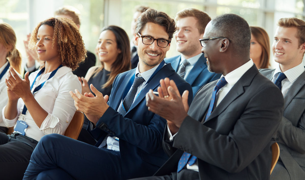 Audience clapping at business seminar, looking at each other